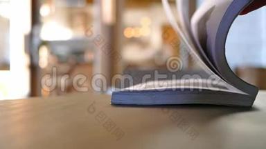 手在咖啡馆里的木桌上翻书页.